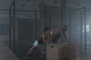 Two individuals engaging in strength training exercises indoors, showcasing fitness and endurance.